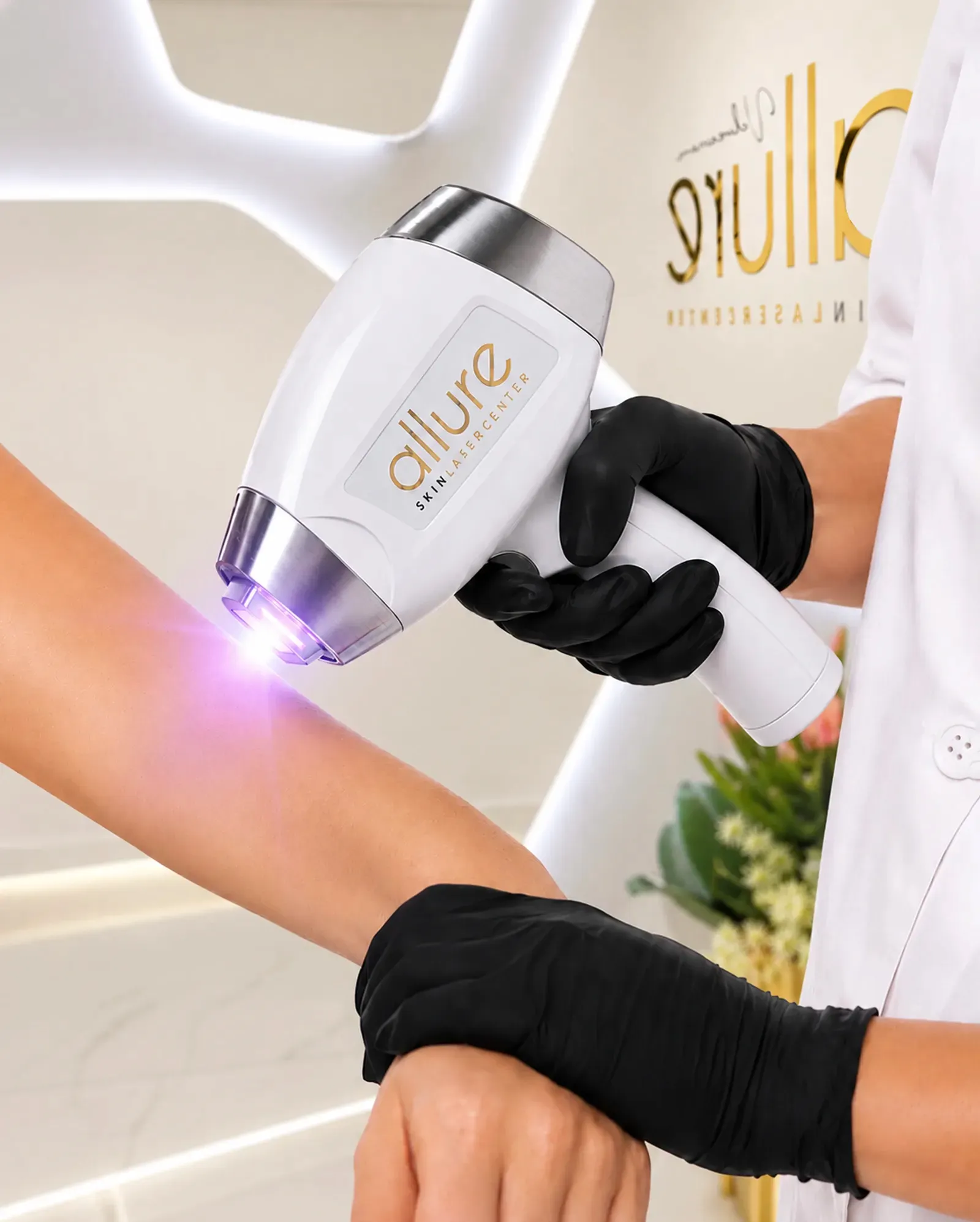 Especialista de Allure Skin con guantes aplica el láser de diodo en el antebrazo de una clienta, con el logo dorado de la clínica al fondo